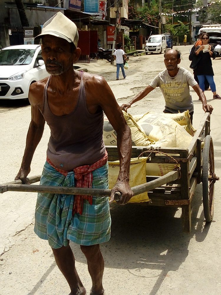 "Man pulling cart with building supplies in street"