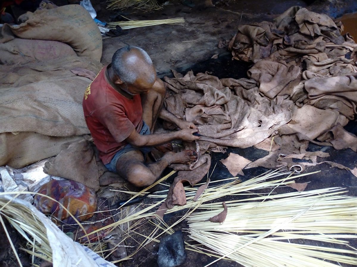 Man sitting on the ground working with hay and cloth