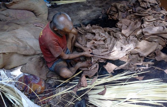 Man sitting on the ground working with hay and cloth