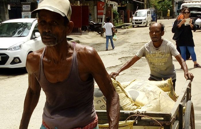 Man pulling cart with building supplies in street